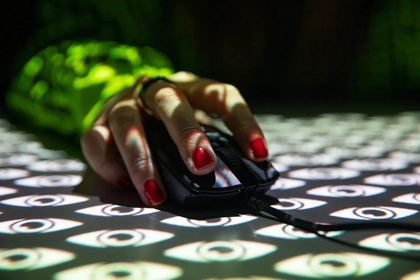 Illustrative image of a hand holding a mouse with stylized eyes projected over it, representing cybercrime