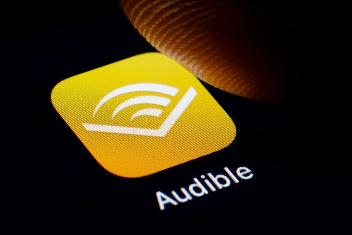 Smartphone exibe o logotipo do Audible em uma composição sobre audiolivros