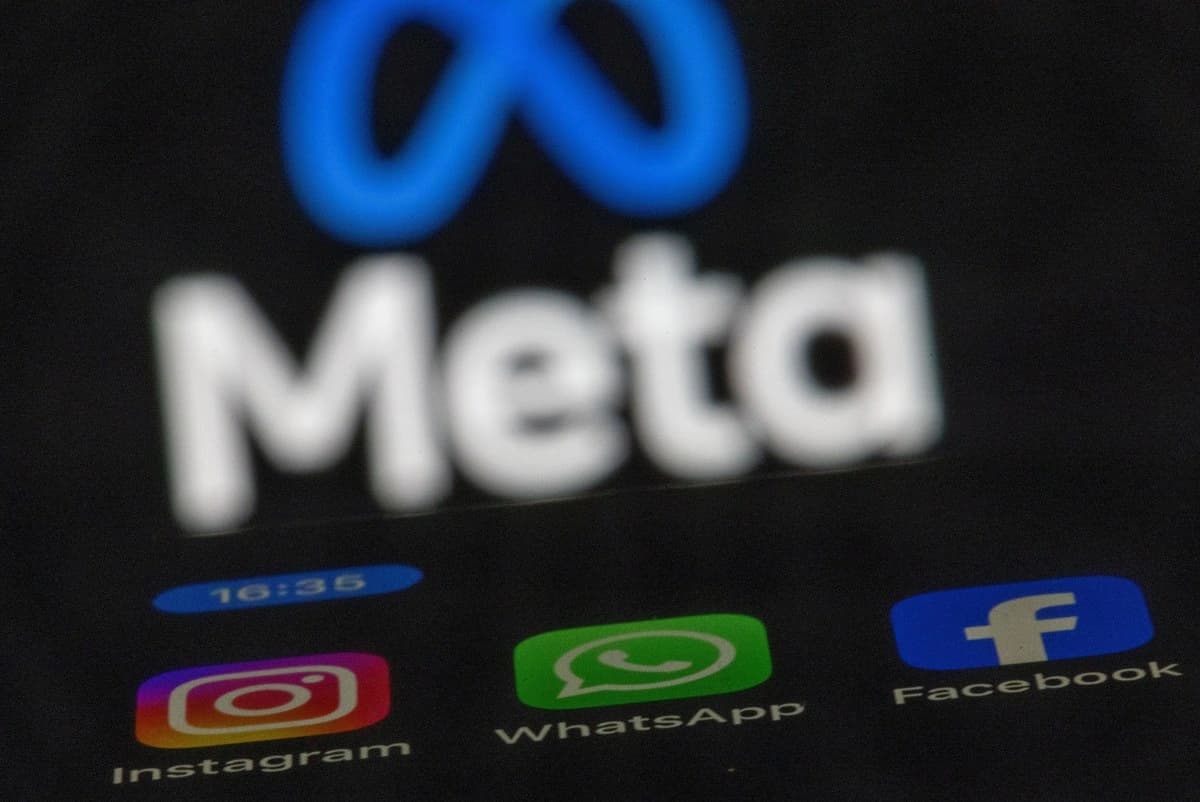 Aplicativos da Meta exibidos em um celular diante do logotipo da empresa
