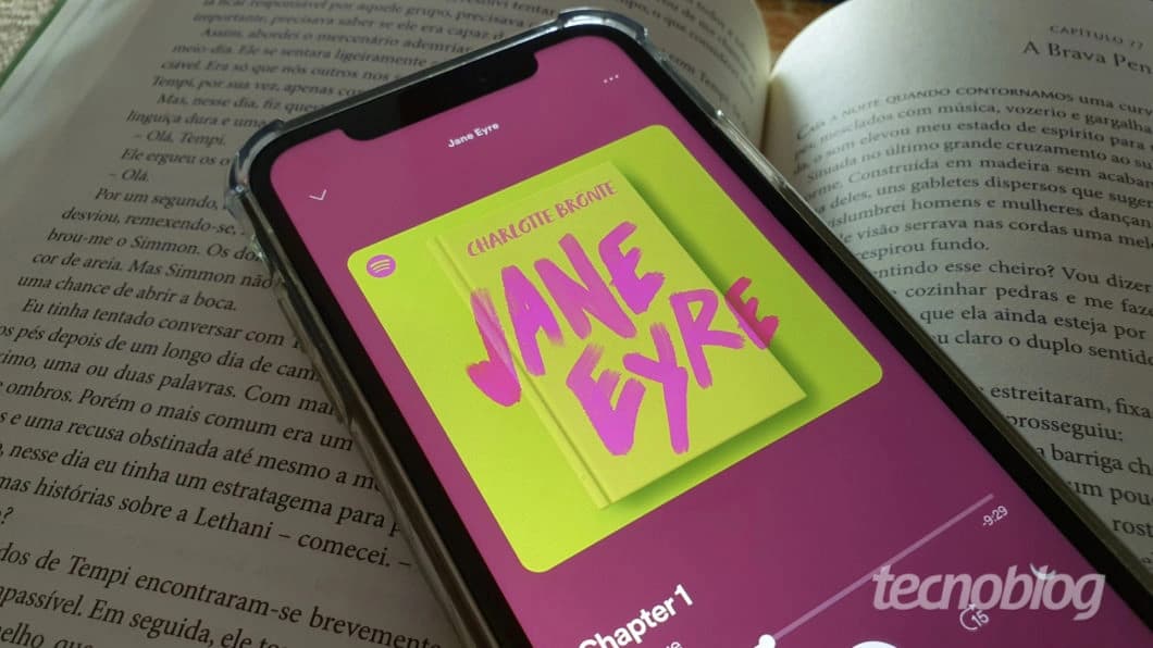 Smartphone com o Spotify aberto sobre as páginas de um livro impresso