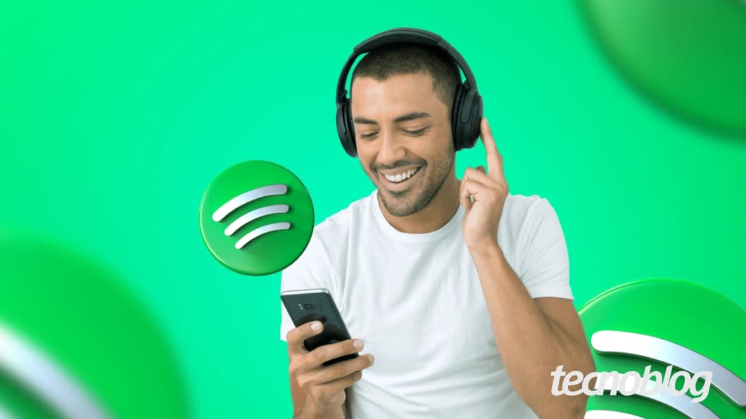 Pessoa segurando um celular com fones de ouvido e logos do Spotify ao fundo