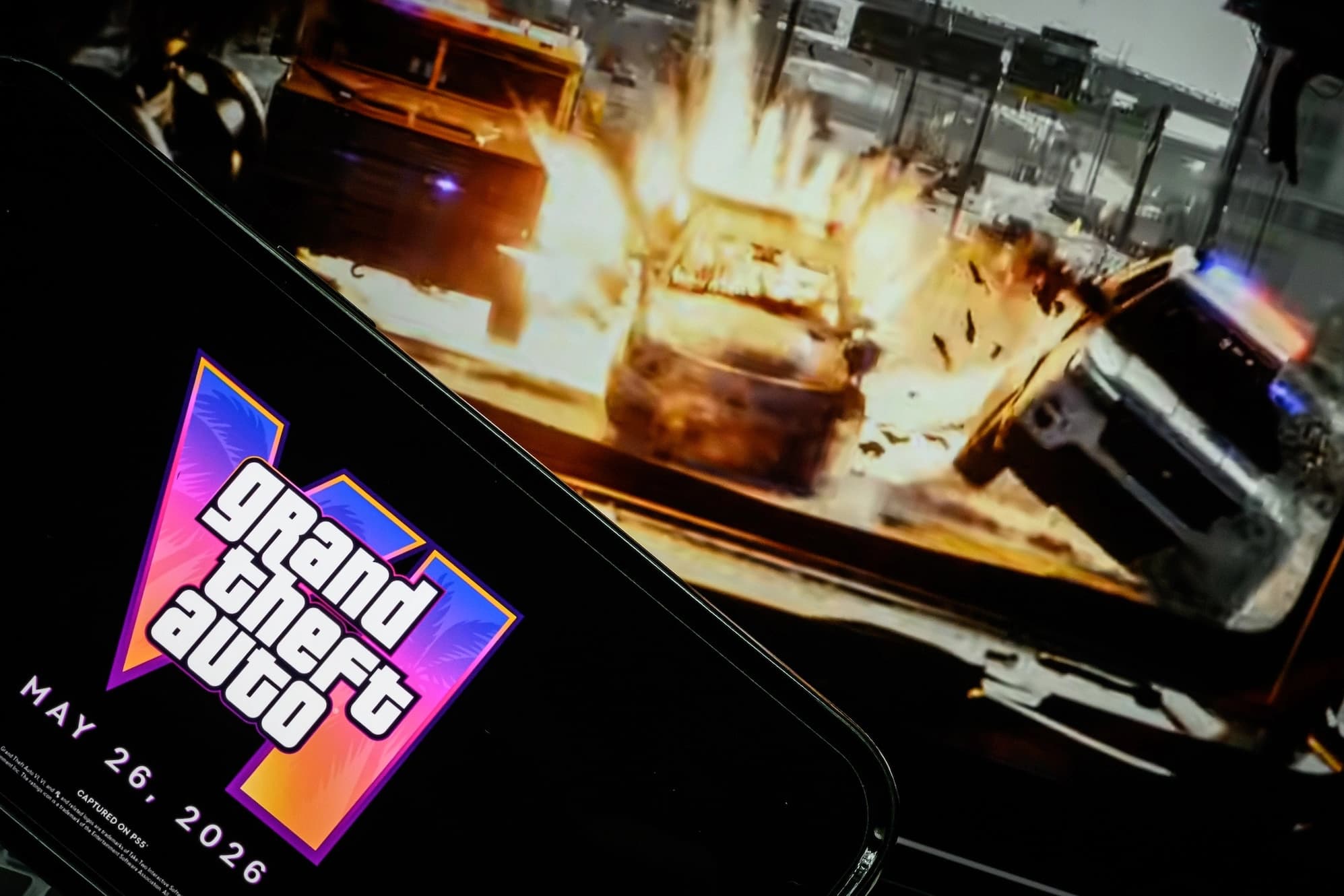 Telefone com o logotipo de Grand Theft Auto VI diante de uma tela com o trailer do jogo