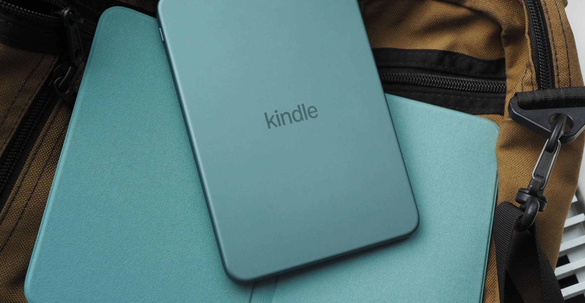 Leitores Kindle da Amazon exibidos em versões de plástico e alumínio sobre uma mesa.